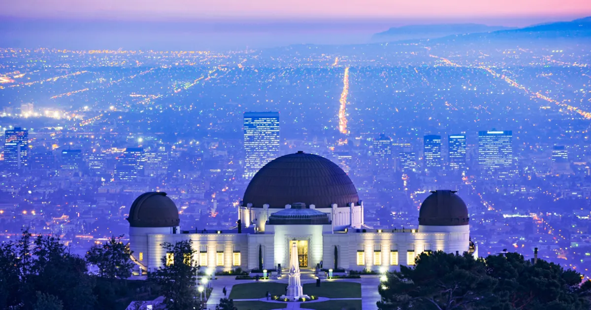 Scenic view of Griffith Observatory showing its iconic white domes against the Los Angeles skyline and Hollywood sign.